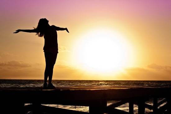 Silhouette of a happy woman  spreading her arms during the golden hour.