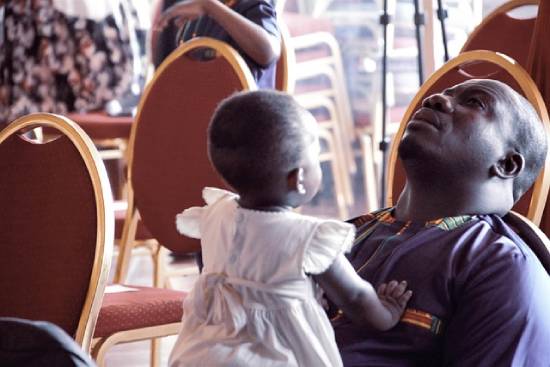 A single father praying while carrying his daughter during a church service.