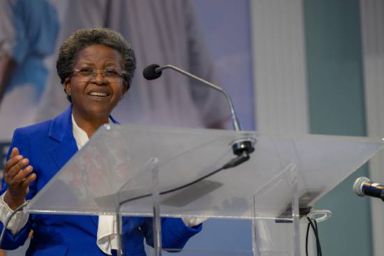 A woman dressed in blue blazer and cream top giving expert talk on health anxiety on a podium.