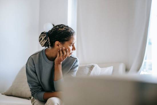 A woman struggling with forgiveness looking over her shoulders while sitting on a bed.