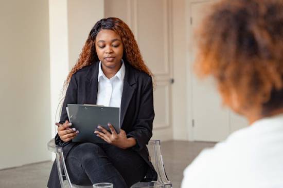 A woman in a white top, black trouser, and a black blazer offering psychotherapy session.