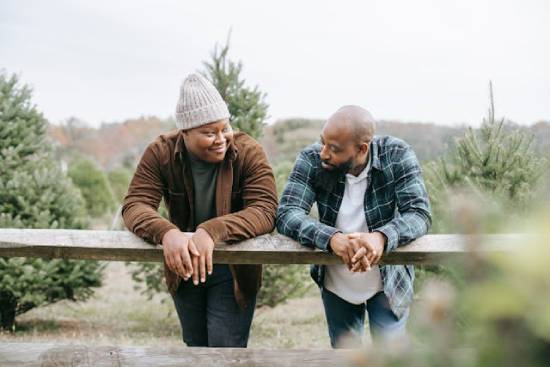 A father nad a son having safe conversations by the fence of a tree garden.