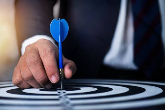 A person holding a blue dart pin setting their targets.
