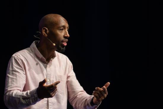 A life coach in a stripped long-sleeved shirt delivering a talk on handling life transitions and change.