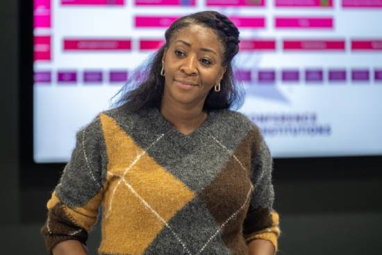 A woman in a sweeter taking a question during a presentation.