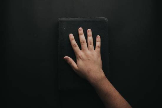 A man holding a black cover Bible.