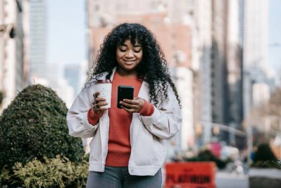 Distracted woman chatting on the street while carrying her takeaway coffee.