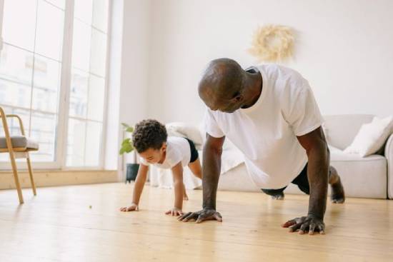 A father and son doing planks in the living room.
