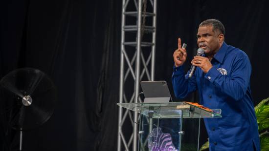 Sermon on Divine Delays A preacher in a navy-blue top giving a sermon on divine delays.