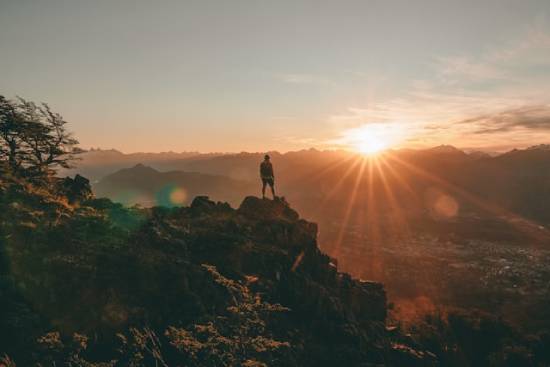 Silhouette of a Man Standing on a Rock at Sunset Silhouette of a man standing on top of a rock looking at the western horizon at sunset.