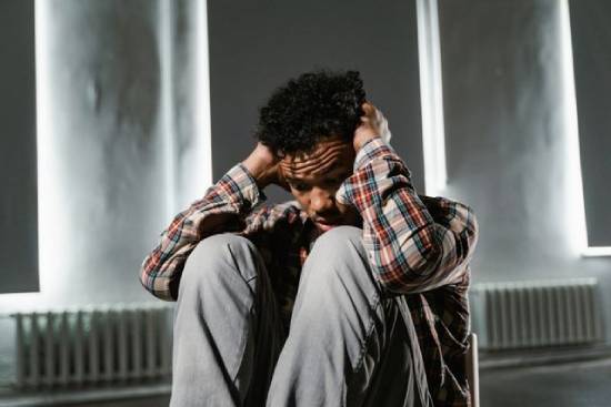 A stressed man sitting down with hands on his head.