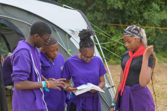 Teenagers Studying the Bible Teenagers studying the Bible outside their tent during a campout.