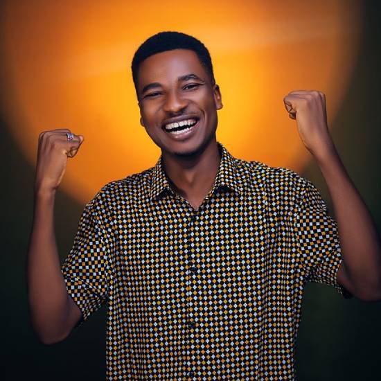 A happy and motivated man in a checked short-sleeved shirt, lifting his hands in celebration.