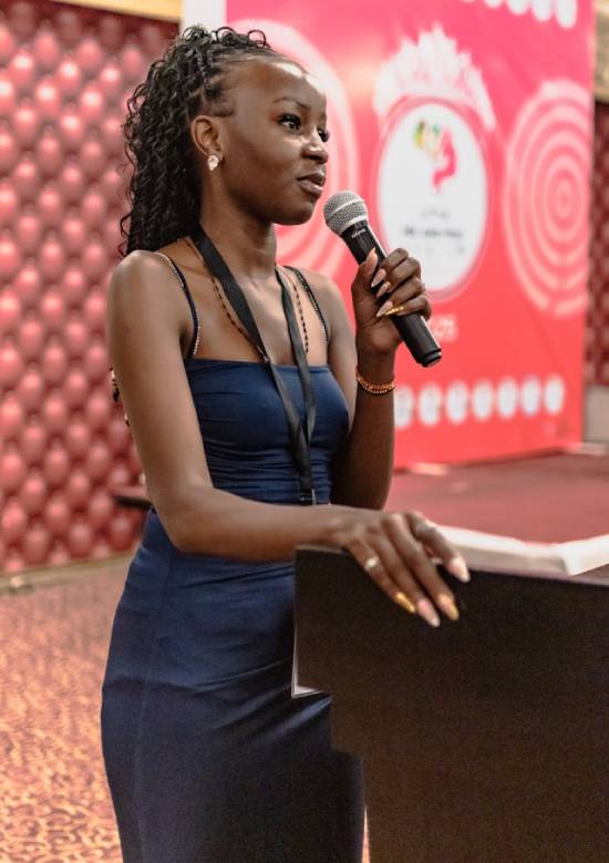 A woman holding a microphone speaking in a conference.