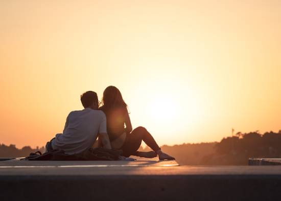 A couple sitting together while on a date during the golden hour.
