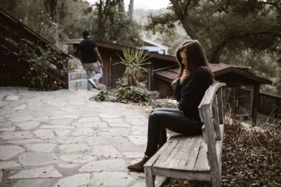 A Man Walking A way on a Woman A man walking away on a sad woman sitting on a wooden bench.