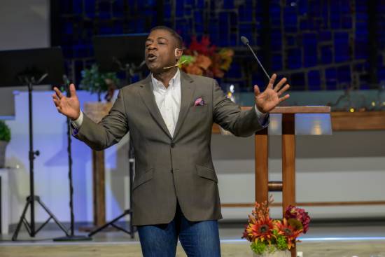 A relationship coach in a grey blazer and jeans giving a talk on trust in relationships.