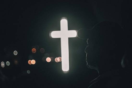 Man Illuminated by the Cross A man wearing a cap illuminated by the cross demonstrating lives transformed by Christianity.