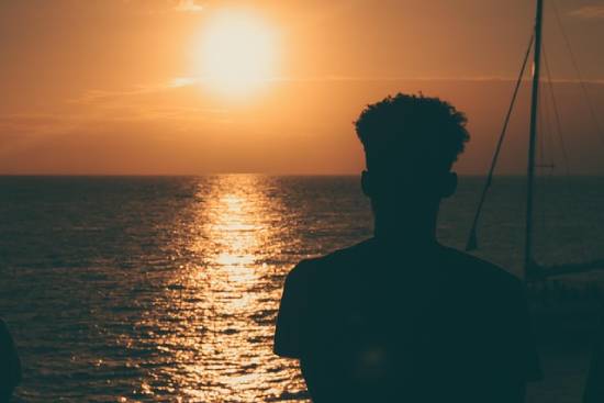 Silhouette of a Person Watching the Sunset Silhouette of a person watching the sunset across calm ocean.