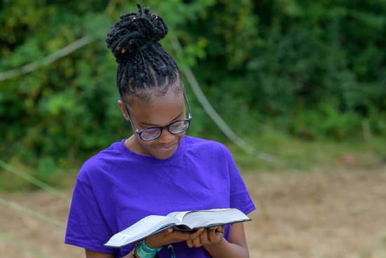 Teenager Reading the Bible A teenage girl in a purple top reading the Bible in the outdoors.