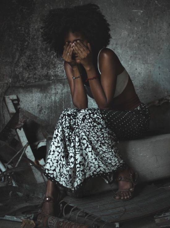 A Woman Overwhelmed With Regret A woman overwhelmed with regret covering her face while sitting on a pavement.